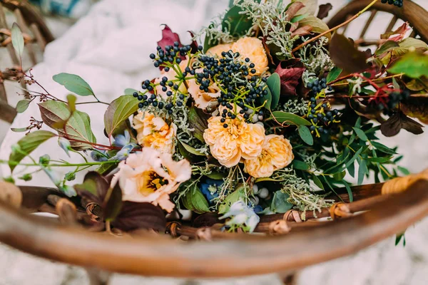 Hermoso ramo de boda que consiste en diferentes flores que yacen en una silla marrón viejo —  Fotos de Stock