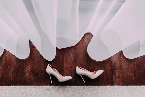 Eleganckie buty ślubne na drewnianej podłodze obok okna. — Zdjęcie stockowe