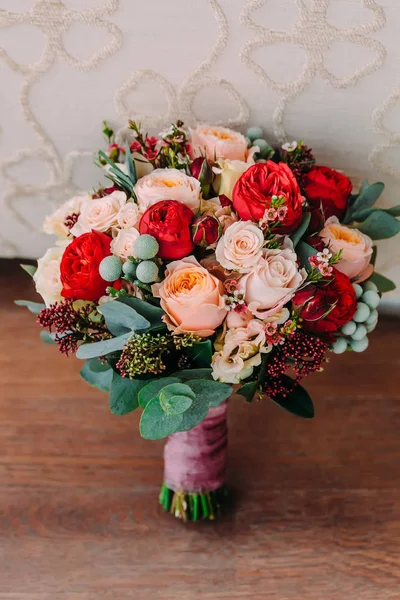 Schöner Hochzeitsstrauß aus roten Blumen, rosa Blumen und Grün liegt auf dem Holzboden. — Stockfoto