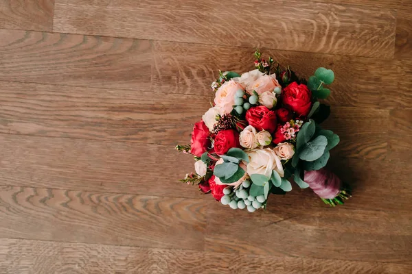 Buquê de casamento de rosas vermelhas e creme em um chão de madeira. Vista superior — Fotografia de Stock