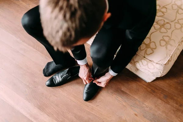 Geschäftsmann bindet Schnürsenkel auf den Boden. Bräutigam bereitet sich morgens vor der Hochzeit vor — Stockfoto