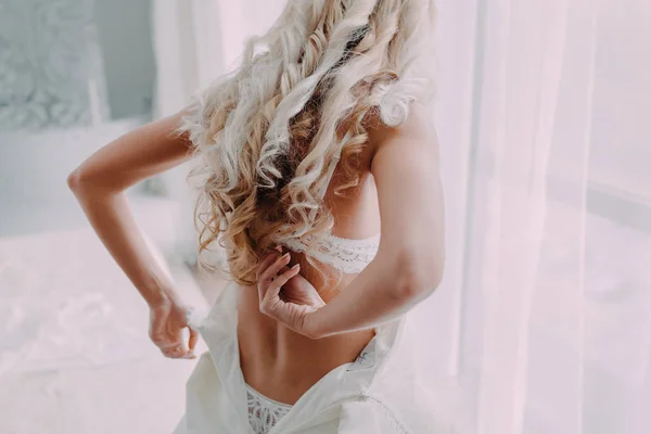 Wunderschöne, blonde Braut im weißen Luxuskleid bereitet sich auf die Hochzeit vor. Die morgendlichen Vorbereitungen. Frau zieht sich an. — Stockfoto