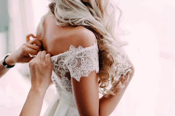 Splendida, sposa bionda in abito bianco di lusso si sta preparando per il matrimonio. Preparativi del mattino. Donna vestita . — Foto Stock