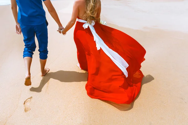 Rückansicht eines verliebten Paares, das mit Fußabdrücken am Sandstrand davonläuft. Händchenhalten — Stockfoto