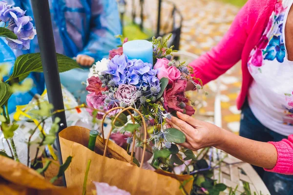 Florist making a flower composition. Wedding details. Woman collecting a composition of different, colorful flowers and a blue candle.