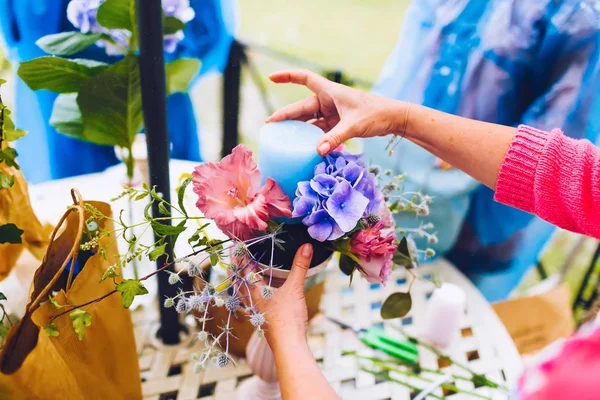 Florist at work, making a flower composition. Wedding details. Woman collecting a composition of different, colorful flowers and a blue candle. — Stock Photo, Image