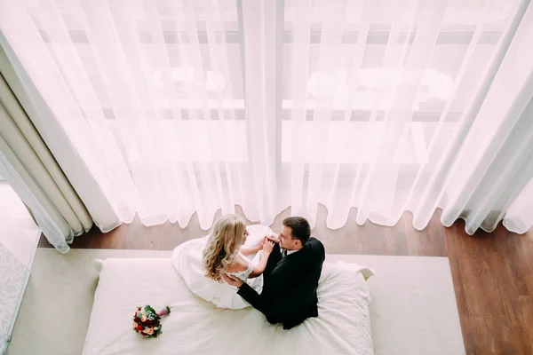 Nowożeńcy ogarnięcie na łóżku w pokoju światło hotel luxury — Zdjęcie stockowe