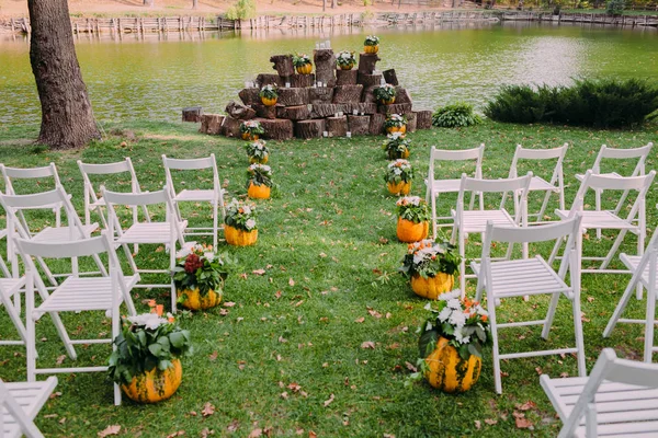 Decoração de casamento com abóboras e flores de outono. Cerimônia ao ar livre no parque. Cadeiras brancas para convidados — Fotografia de Stock