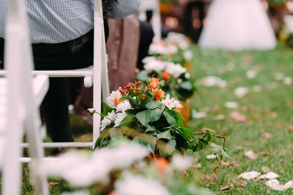 Διακοσμητικά από λευκό και πορτοκαλί λουλούδια με διακόσμηση πράσινα φύλλα. Υπαίθριος γάμος — Φωτογραφία Αρχείου