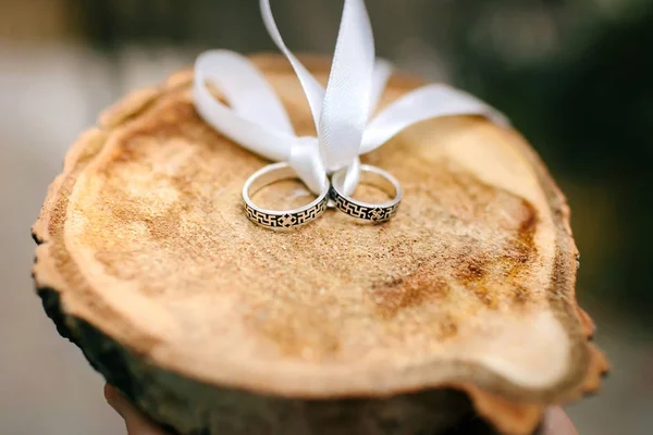 Bruiloft zilveren ringen op hout gesneden die verbond met wit lint — Stockfoto