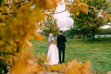 Mutlu gelin ve Damat Düğün gününde ellerinde beyaz balonlarla yeşil çimenlerin üzerinde büyük zaman ayakta olması.