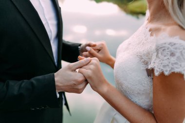 Düğün. Güzel gelin ve damat düzenliyoruz. Genç çift yüz yüze ve gölün karşı dururken birbirlerine bakarak ayakta yan görünüm.