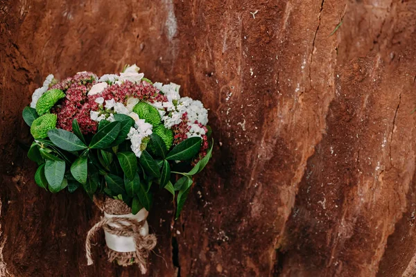 Rustikaler Hochzeitsstrauß mit verschiedenen Blumen und Grüntönen auf Holzgrund — Stockfoto