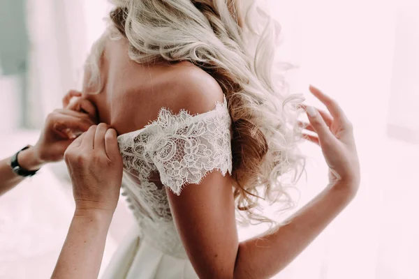 Družička pomáhá upevnit svatební šaty nevěsty před obřadem. Svatební koncept — Stock fotografie