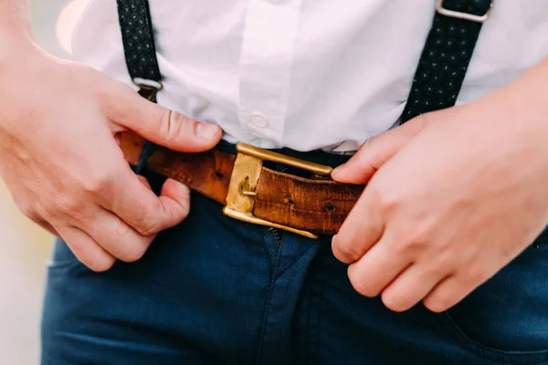 Mens tillbehör. Hipster att sätta på ett brunt läderbälte. Manliga händer närbild. Kläder-konceptet. — Stockfoto