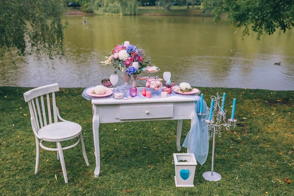 Bruiloft Decoratie in de stijl van boho, floral regeling, ingericht tafel in de tuin in de buurt van het meer. Feestelijke tafel geserveerd voor twee — Stockfoto