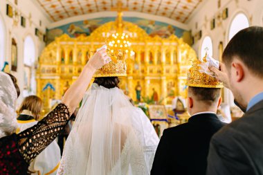 Yeni evliler tanıkların altın kron kilisede gelin ve damat başlarının üzerinden tutun