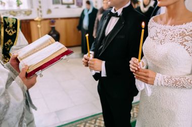 Tanınmayan gelin ve damada Hıristiyan düğün töreni sırasında kilisede. Bir rahip İncil ile elleri.