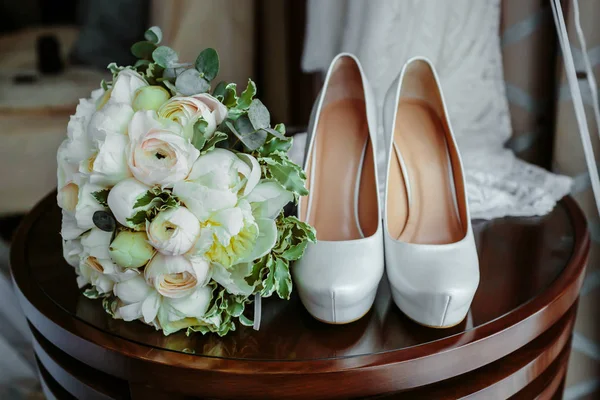 Ramo de rosas blancas y elegantes zapatos de boda en mesa de madera — Foto de Stock