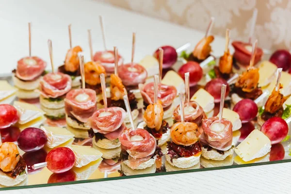 Servicios de catering. Bandeja de vidrio con aperitivos con brie, uva, tocino y camarones en un restaurante. Snacks antes de la boda —  Fotos de Stock