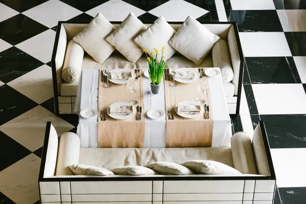 Elegante mesa de comedor blanca y sofás. Interior minimalista en monocromo. Concepto blanco y negro. Restaurante vacío vista superior . —  Fotos de Stock