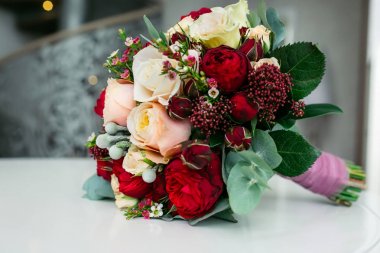 Güzel gelin buketi beyaz ve Şeftali güller, kırmızı peonies ve bir beyaz masaya diğer çiçek ile. Yakın çekim