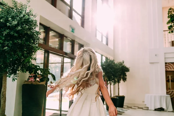 Beautiful young cheerful bride with a smile in a white dress is spinning around itself in sunlight. A moment of carefree and true happiness. Happy blonde having fun in dance — Stock Photo, Image