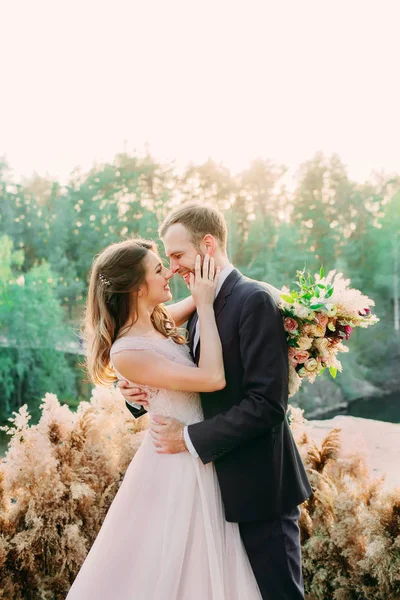 Sevecen yeni evlilerin burunlarına dokunan portresi. Gelin ve damat doğada poz veriyor. Düğün. — Stok fotoğraf