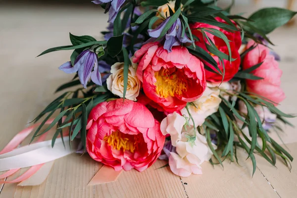Rustikaler Hochzeitsstrauß mit weißen Rosen, purpurroten Pfingstrosen und Grüntönen auf einem Holzboden. Nahaufnahme. — Stockfoto