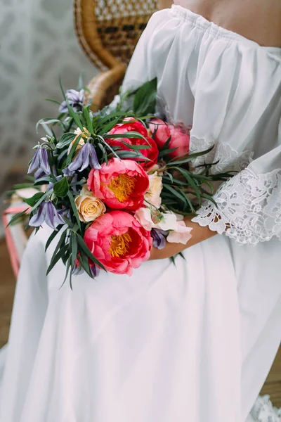 La mariée tient dans ses mains un bouquet de mariage rustique avec des roses blanches et des pivoines pourpres. Gros plan — Photo