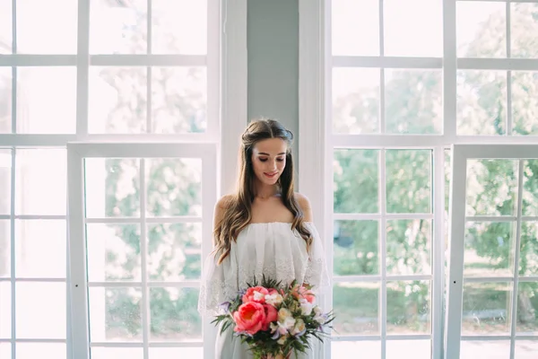 Panna młoda trzyma w rękach rustykalny bukiet ślubny z białymi różami i purpurowymi piwoniami na tle okna. Zbliżenie — Zdjęcie stockowe