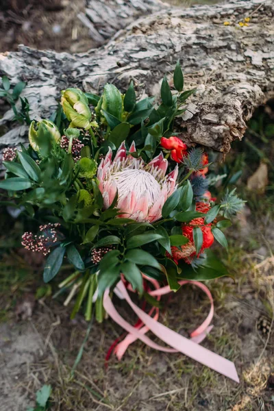 A rustic wedding bouquet with pink ribbons near the log. Artwork — Stock Photo, Image