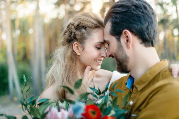 A young couple smile and touching foreheads. Autumn wedding ceremony outdoors. Bride and groom look at each other with tenderness and love. Close-up portrait — Stock Photo, Image