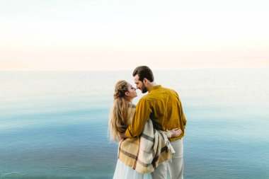 Güzel bir çift deniz arka plan üzerinde benimsemiş. An önce öpücük. Sahilde romantik tarih. Arkadan görüntüleyin. Düğün. Sanat