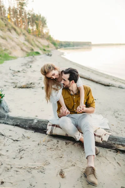 一对年轻夫妇是乐趣和拥抱在沙滩上。美丽的女孩拥抱她的男友从后面。婚礼。图稿 — 图库照片