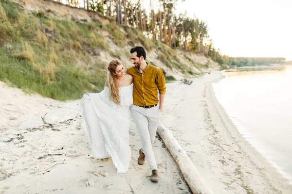 Genç bir çift eğleniyor ve deniz kıyı şeridi üzerinde yürüme. Hassasiyet ile birbirine bakarak yeni evliler. Sahilde romantik tarih. Düğün. Sanat — Stok fotoğraf