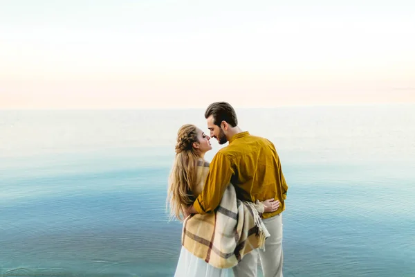 A beautiful couple is embracing on the sea background. Moment before the kiss. Romantic date on the beach. View from the back. Wedding. Artwork — Stock Photo, Image