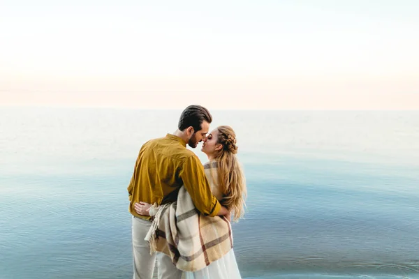 Ett vackert par omfamnar på havet bakgrunden. Stund innan kyssen. Romantisk datum på stranden. Visa från baksidan. Bröllop. Konstverk — Stockfoto