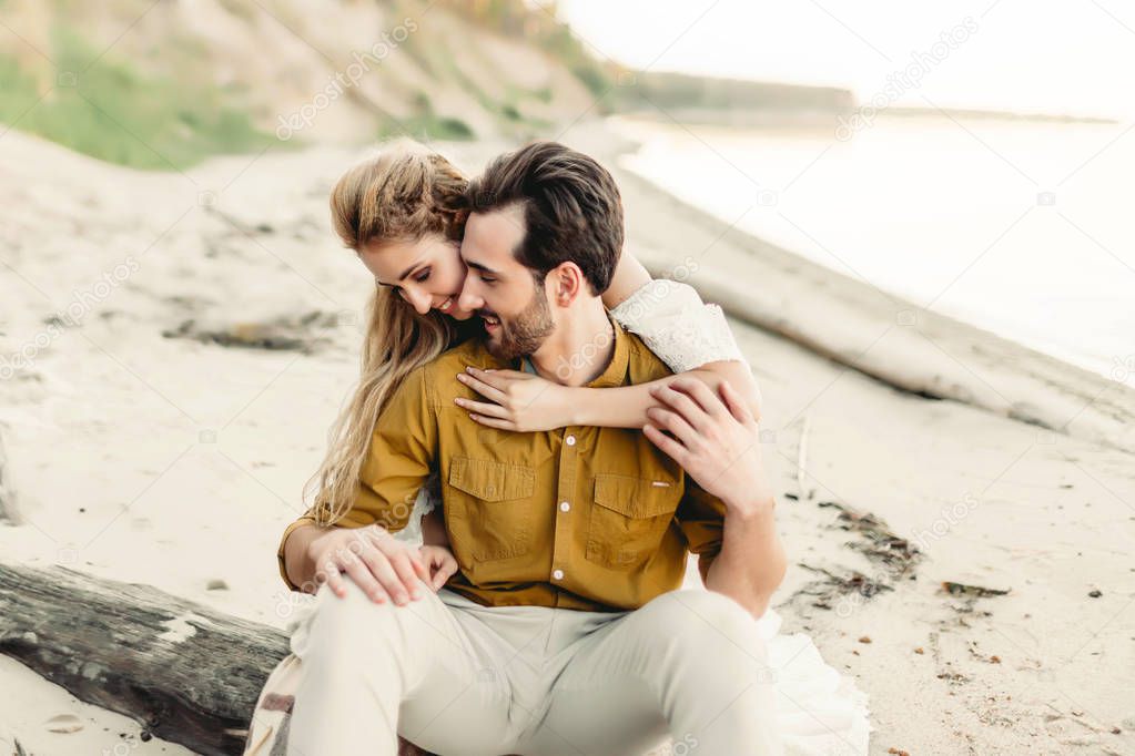 A young couple is having fun and hugging on the beach. Beautiful girl embrace her boyfriend from back. Wedding walk. A newlyweds looks at each other. Artwork