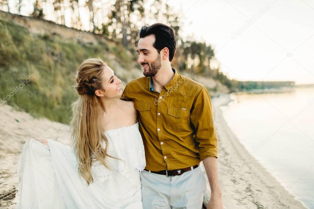 A young couple is having fun and walking on the sea coastline. Newlyweds looking at each other with tenderness. Romantic date on the beach. Wedding. Artwork