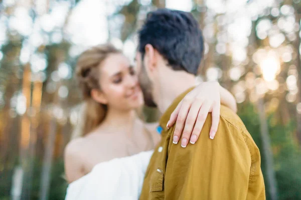 La novia está abrazando a los novios de nuevo por su mano tierna. Los recién casados borrosos se miran con ternura y amor. Primer plano. Obra de arte — Foto de Stock