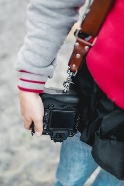 Fotoğraf makinesi üzerinde bir deri kayışı. Fotoğrafçı bir kamera elinde tutar. Yakın çekim. A