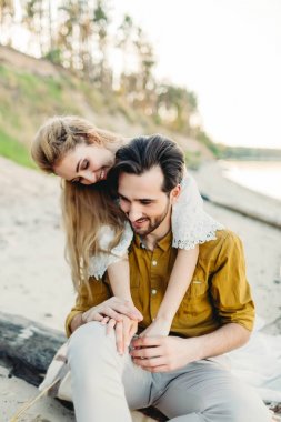 Genç bir çift eğleniyor ve sahilde sarılma. Güzel kız sevgilisini arkadan kucaklamak. Düğün. Sanat