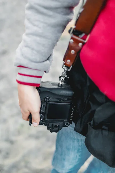 Cámara fotográfica en una correa de cuero. El fotógrafo sostiene una cámara en la mano. Primer plano. A — Foto de Stock