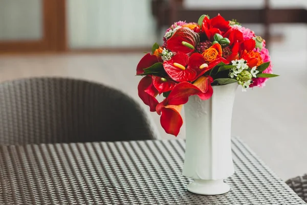 A bouquet of different red flowers in a vase on a table. Close-up. Artwork — Stock Photo, Image