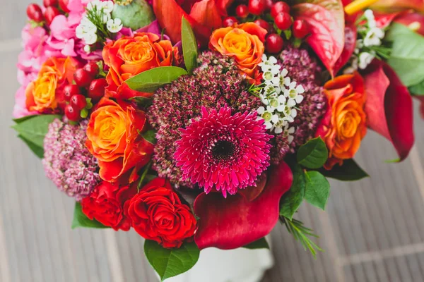 Stylové svatební kytice s oranžovou, crimson a bordeaux růží, máku a další květiny a zelené na dřevěné pozadí. Detail. — Stock fotografie