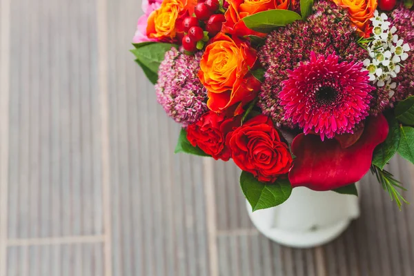 Романтичний весільний букет з помаранчевими, малиновими та бордоськими трояндами, маком та іншими квітами та зеленню на розмитому дерев'яному тлі. Крупним планом . — стокове фото