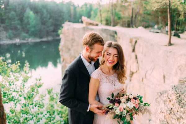 Çekici çift yeni evli gelin ve damat gülmek ve gülümsemek, mutlu ve neşeli an. Düğün töreni açık havada — Stok fotoğraf