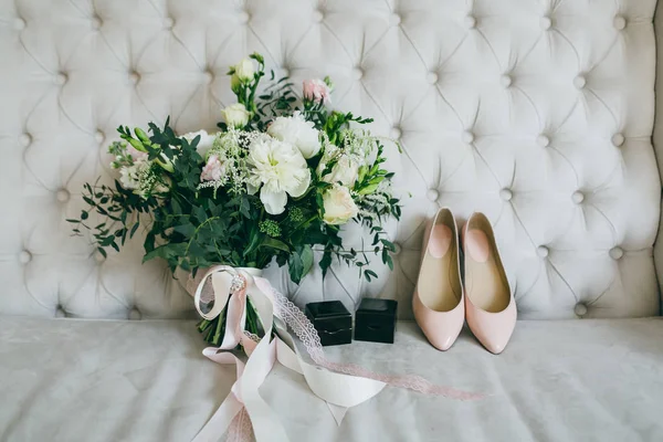 Bouquet de mariage, chaussures de mariée roses et boîtes noires avec anneaux sur un canapé de luxe. À l'intérieur. Oeuvres — Photo