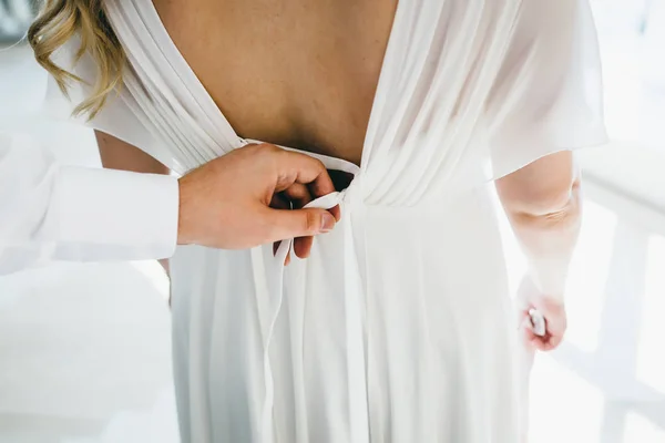 Bräutigam hilft, ein Hochzeitskleid der Braut vor der Zeremonie zu befestigen. Hochzeitskonzept. Nahaufnahme-Kunstwerk — Stockfoto